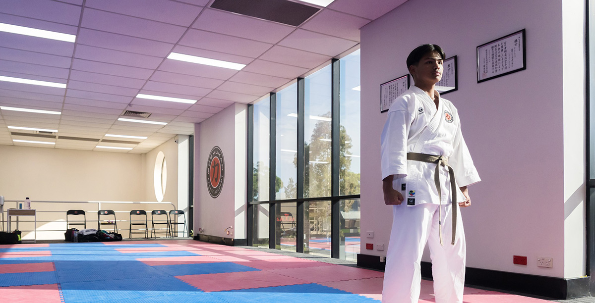 Our student Biensy standing in uniform inside Goshukan Karate Academy's Seven Hills karate dojo